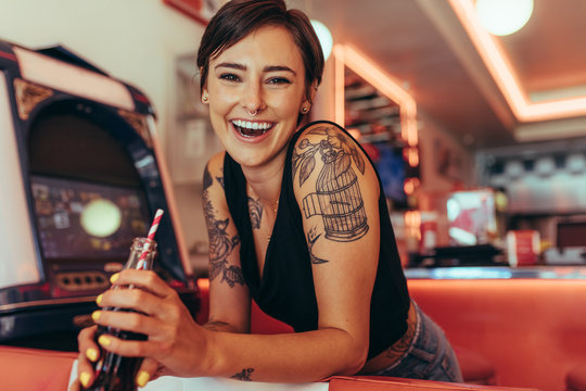 Smiling woman at a diner drinking soft drink