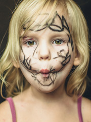 The little girl painted her face with a marker. Makeup for Halloween.