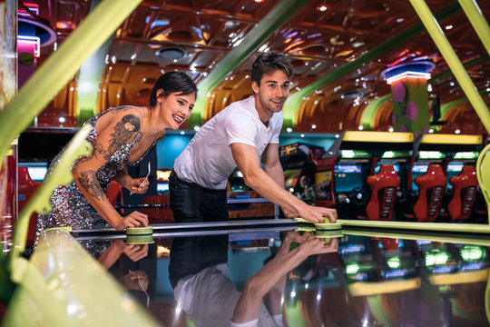 Couple enjoying a game of air hockey at a gaming arcade