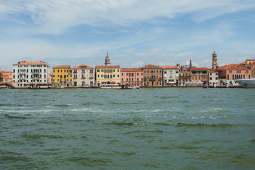 Fototapeta na wymiar Venetian channel view at the city in one horizontal line of urban architecture, buildings, one of the Venice Bridge, free space