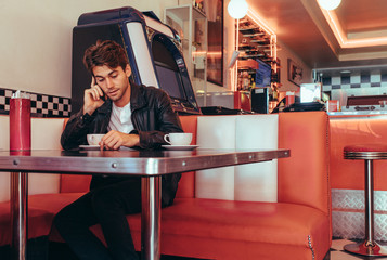 Man talking over mobile phone sitting at a restaurant