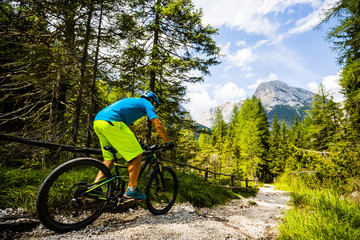 Tourist cycling in Cortina d'Ampezzo, stunning rocky mountains on the background. Man riding MTB enduro flow trail. South Tyrol province of Italy, Dolomites.