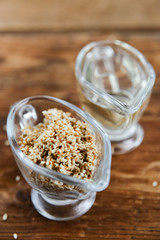 sesame seed oil and sesame seed oil in glass Cup on natural wooden background, healthy food concept, organic food.