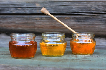 three cans of honey of different colors on wooden background