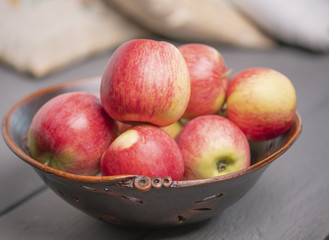 Fototapeta na wymiar Красные деревенские яблоки в старой вазе на сером столе