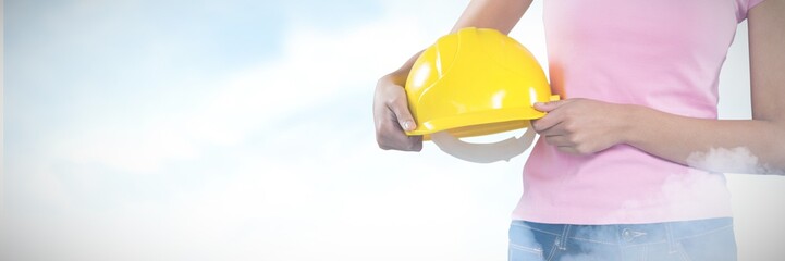 Composite image of woman holding hard hat against grey