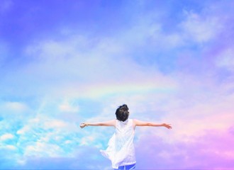 Happy woman under beautiful blue sky with rainbow.