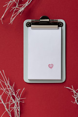 Clipboard on red background. Flat lay, top view trendy with heart
