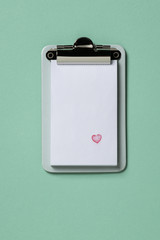 Clipboard on turquoise background. Flat lay, top view trendy for banner with heart