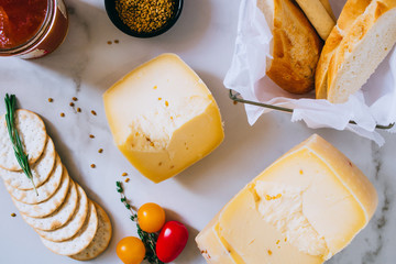 Cachotta cheese with with fenugreek, jam, baguette, crackers, rosemary and thyme on marble