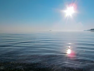Gordijnen Landscape with water, sun with bright sunbeams in the sky and a boat on skyline. Beautiful view of Lake Huron, the Great Lakes region, USA. © mivod