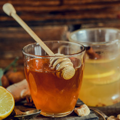 Vitamin healing tea with lemon and honey, ginger and spices on wooden background in rustic style. The concept of spring beriberi and colds. Square image.