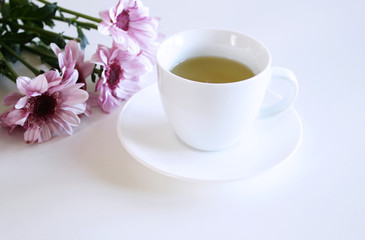 A cup of tea and pink Chrysanthemum flower on the table.Blurred background.
