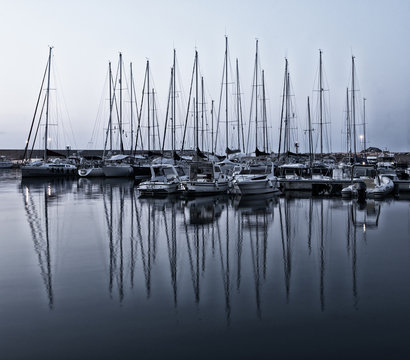 Boats moored at Alghero harbor at sunset, Sardinia, Italy