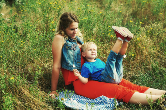 A young mother is resting with her son on a country walk