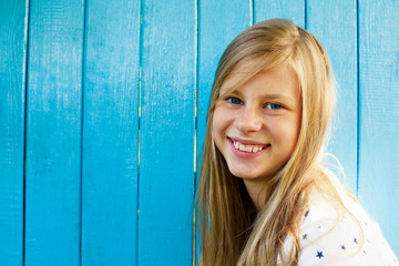Portrait of a beautiful blond teenage girl on a blue wall background