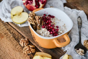 Breakfast: granola with pomegranate and walnuts and green Apple on natural wooden background rustic. The concept of healthy and high-carbon nutrition.