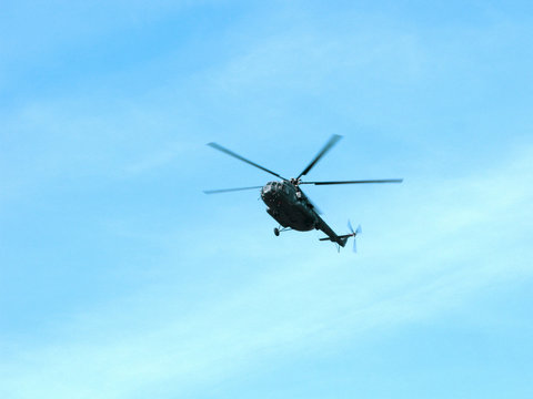Military helicopter is flying in blue peaceful sky.