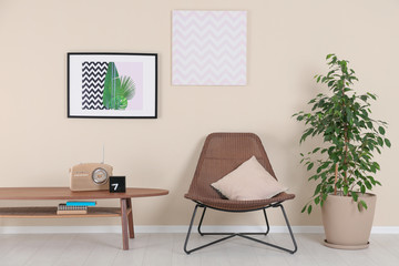 Obraz premium Stylish living room interior with armchair and houseplant near beige wall