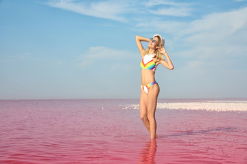 Naklejka premium Beautiful woman posing in pink lake on sunny day