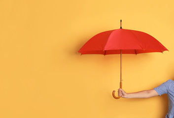 Person holding bright open umbrella on color background with space for design