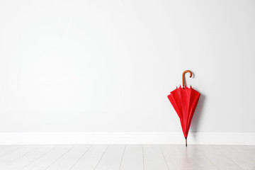 Beautiful umbrella on floor near white wall with space for design - obrazy, fototapety, plakaty