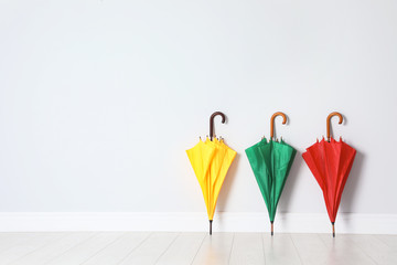 Beautiful bright umbrellas on floor near white wall with space for design