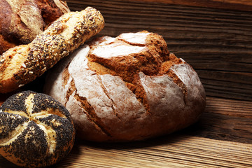 Different kinds of bread and bread rolls on board from above. Kitchen or bakery