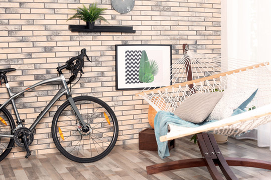 Modern bicycle and hammock in stylish room interior