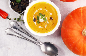 Roasted pumpkin and carrot soup with cream and pumpkin seeds on stone background.