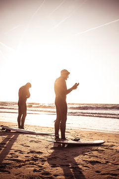 boys with surfboard at sunset at beach