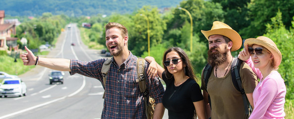 Friends hitchhikers looking for transportation sunny day. On way to vacation. Company friends travelers hitchhiking at edge road nature background. Begin great adventure in your life with hitchhiking