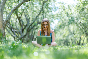 beautiful girl sitting in the Park with her laptop in Lotus position