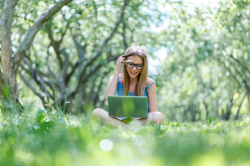 beautiful girl sitting in the Park with her laptop in Lotus position