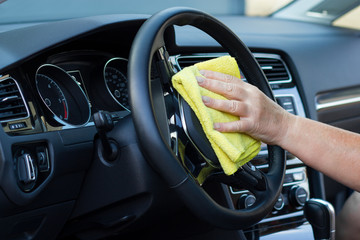 Hand with cloth cleaning car interior