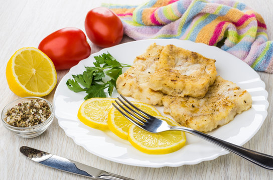 Fried Pollock With Lemon In Plate, Fork, Tomatoes, Condiment, Napkin