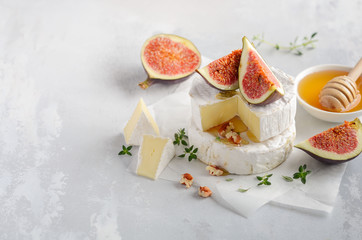 Brie or camembert cheese with figs, thyme, honey and nuts, selective focus.