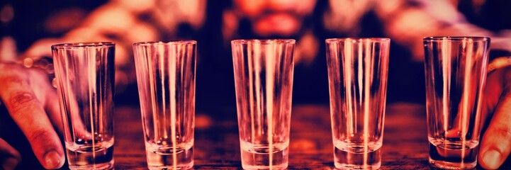 Waiter placing shot glasses on counter