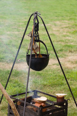 A medieval cauldron or cooking pot suspended on a hanger over an open fire