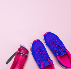 Ultra blue violet pink female sneakers and water bottle on pastel pink background flat lay top view with copy space. Sports shoes, fitness, concept of healthy lifestile, everyday training.