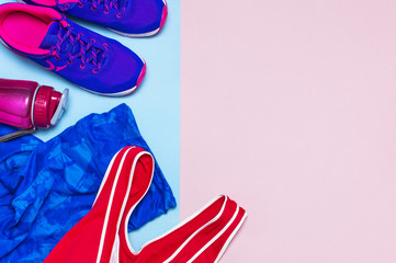 Ultra violet female sneakers, pink top blue sporting leggings and water bottle on pastel pink background flat lay top view with copy space. Sports shoes, fitness, concept of healthy lifestile.
