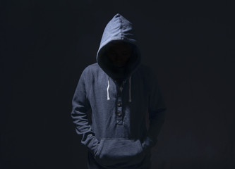Mysterious man with hoodie in silhouette on black background. committed a crime concept.