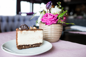Creamy cheesecake with chocolate cookies and cream biscuits. Oreo cake and a beautiful vase with flowers on the table. A beautiful bouquet of flowers from roses and tulips.