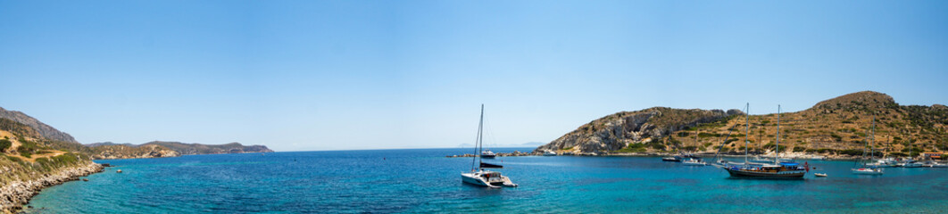 Fototapeta na wymiar Picturesque bay between the Datca Peninsula and the island of Knidos, indented coastline between of mediterranean and aegean seas with beautiful turquoise water, sailboat in the middle, Turkey