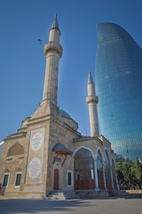 BAKU, AZERBAIJAN : The Mosque of the Martyrs Sehidler Mescidi Mosque, Turkish Mosque with the Flame Towers skyscraper in the background in Baku, Azerbaijan, at sunset.
