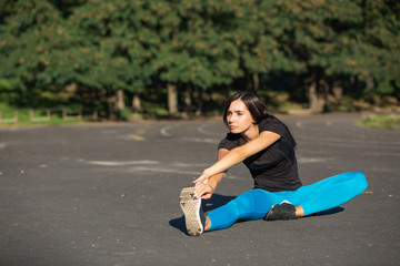 Gorgeous sporty woman stretching before workout at the stadium. Space for text