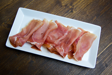 Ham on tray on a wooden table seen from above