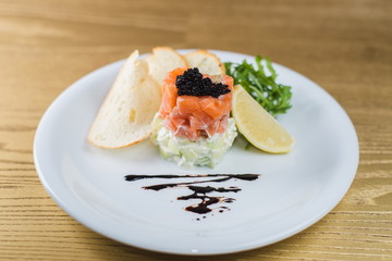 Rolls of salmon with cheese and salad on a white plate