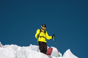Fototapeta na wymiar A freerider skier in complete outfit stands on a glacier in the North Caucasus. Skier preparing before jumping from the glacier