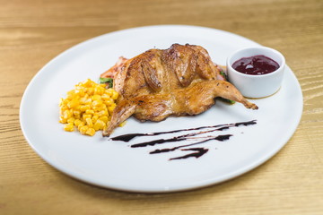 fried quail with corn and sauce on a white plate